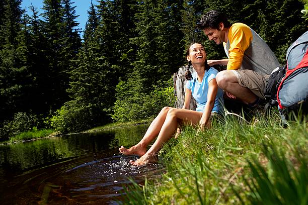 coppia seduta in acqua, donna con i piedi in acqua - looking over shoulder looking men looking up foto e immagini stock