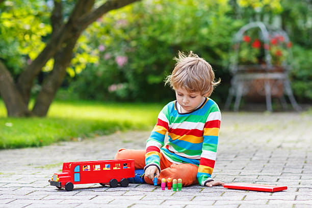 istock cute blond kid boy playing with red school bus toy 521199705