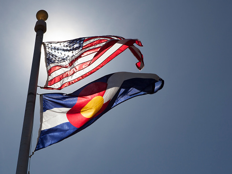 The American and State of Colorado flags flying on a sunny day.