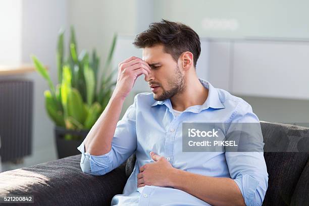 Man On Sofa Having Headache Stock Photo - Download Image Now - Men, Stomachache, Pain