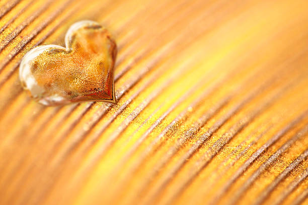 Shiny small golden heart on gold powder background