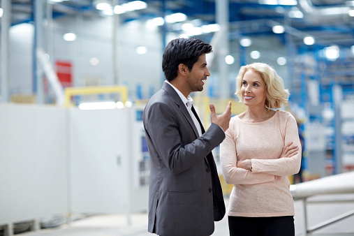 Young businessman having a conversation with senior female colleague at factory shopfloor