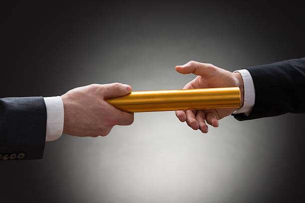 Two Hands Passing A Golden Relay Baton Close-up Of Two Businessman's Hand Passing A Golden Relay Baton relay photos stock pictures, royalty-free photos & images