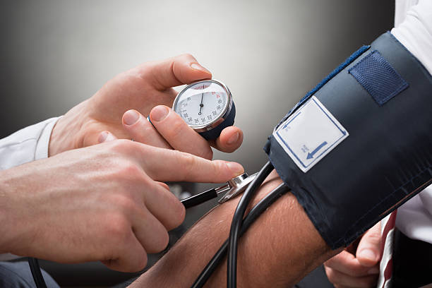 doctor revisando la presión arterial de un paciente - hipertension fotografías e imágenes de stock