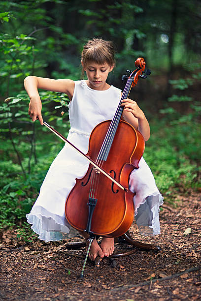 istock Little girl playing cello in forest 521203064