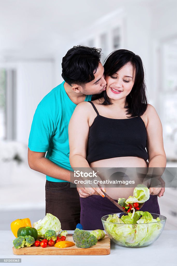Man kiss his pregnant wife Portrait of asian husband kiss his pregnant wife in the kitchen Abdomen Stock Photo