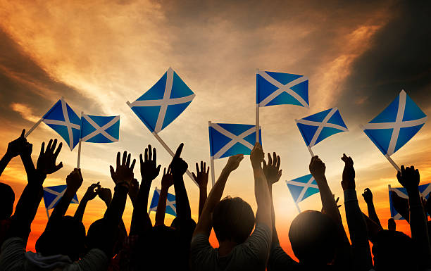 istock Group of People Waving Scottish Flags in Back Lit 521203959