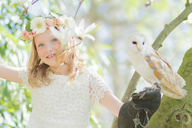 biondo ragazza in con un gufo in un albero di magnolia - child portrait fine art portrait multi colored foto e immagini stock