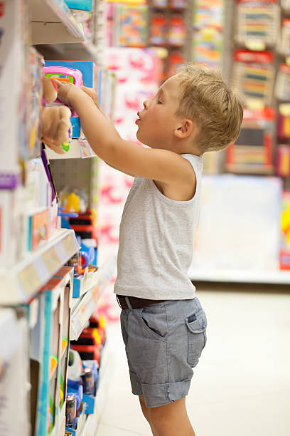 Boy choosing toy in the shop Little boy choosing toys on the high shelf in the shop toy store stock pictures, royalty-free photos & images