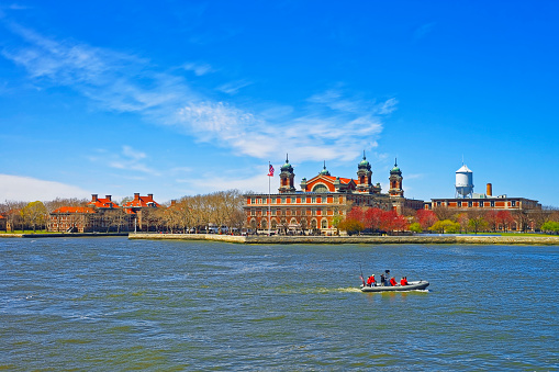 New York City, USA - April 25, 2015: View on a boat and Ellis Island, USA, in Upper New York Bay. Tourists nearby