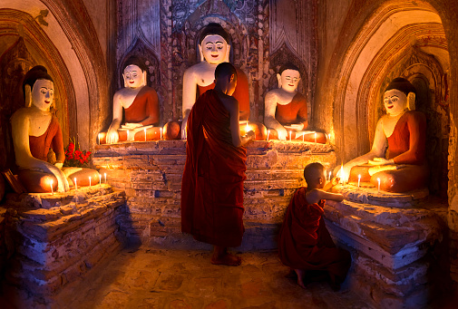 Two young buddhist monks praying inside the temple