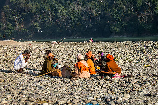 Rishikesh, India - December 31, 2014: Unidentified Indian sadhus siting on the beach near holy River Ganga in Rishikesh. The sadhus are the Indian holy men and respected for their renunciation