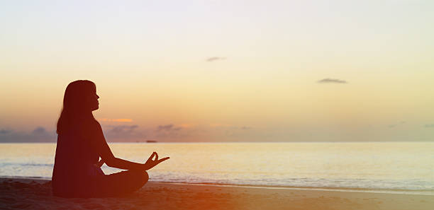 istock young woman doing yoga on sunset beach 521212056