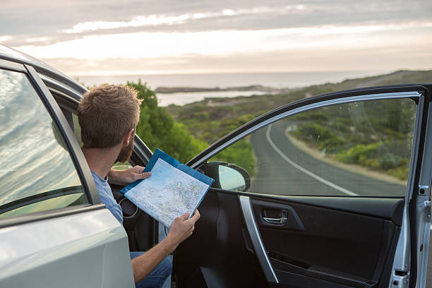 istock Man on road trip in Australia reads map for directions 521223512
