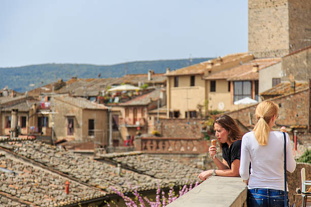 San Gimignano, Italy - April 7, 2016: Tourists enjoying gelato, or ice-cream, while overlooking the rooftops of San Gimignano in Italy