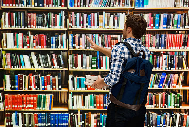 istock Rear view of student waving hand in library 521227348