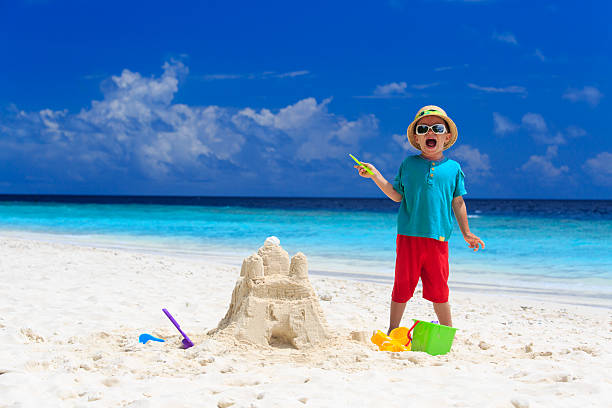 istock happy little boy with built sandcastle on beach 521227553