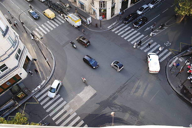 Four road junction with cars in Paris Four road junction with cars in Paris and people crossing the street crossroads sign stock pictures, royalty-free photos & images
