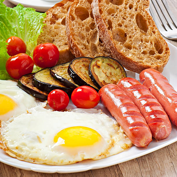 istock English breakfast - fried eggs, sausages, eggplant and tomatoes 521228511
