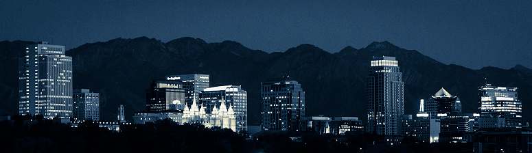 A true representation of the Salt Lake City, Utah skyline with mountains in the background. Taken at night, and processed with a blue tone. All building logos and names remain.