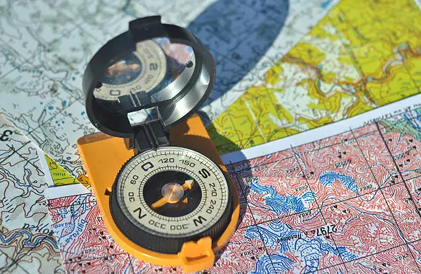 The compass on the map. Open the compass lies on topographic maps and casts a shadow over them.