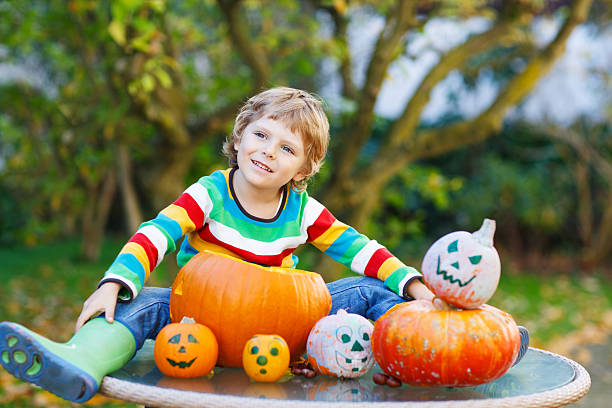 istock Little kid boy making jack-o-lantern for halloween in autumn gar 521233321