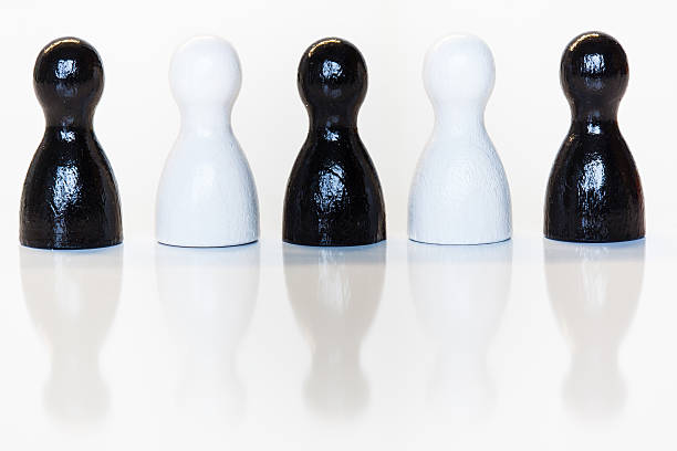 Group of wooden toy figurines, black and white, with reflection on bottom. Diversity, ethnicity or racial issues concept.