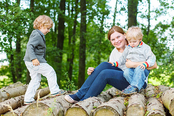 istock Mother and two little children having fun in summer forest 521248537