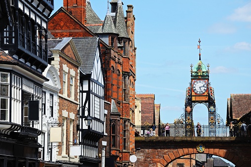 Chester, United Kingdom - July 22, 2014: Eastgate Clock which was erected in 1899 to celebrate the diamond jubilee of Queen Victoria in 1897 with people standing on the bridge looking at the view, Chester, Cheshire, England, UK, Western Europe.