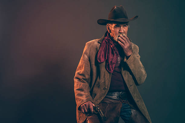 タバコの喫煙シニアカウボーイにグレイのヒゲと茶色の帽子ます。 - cowboy hat real people red gray ストックフォトと画像