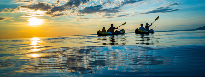Silhouette  OF Young family enjoy sea kayaking in the sunset.