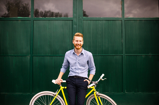 Handsome male leaning on a modern bicycle and smiling on a green background