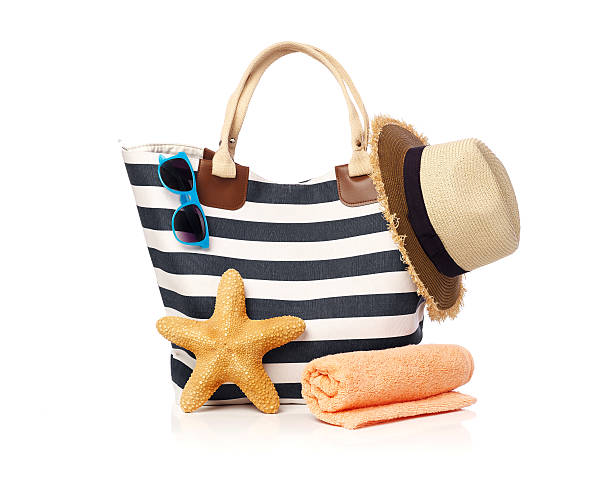 Beach bag concept Beach bag with towel, starfish, straw hat and sunglasses isolated on white beach bag stock pictures, royalty-free photos & images