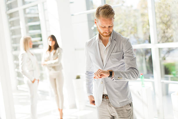 istock Young man looking at watch in the office 521260126