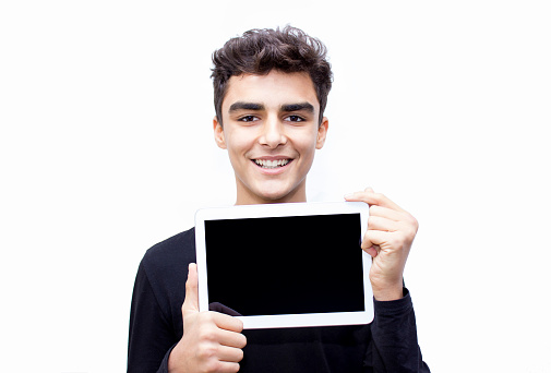Portrait of smiling child showing empty digital tablet. There is copy space for your text or image on digital tablet's screen. Young man looking at camera with positive emotion. Horizontal composiiton. Studio shot.
