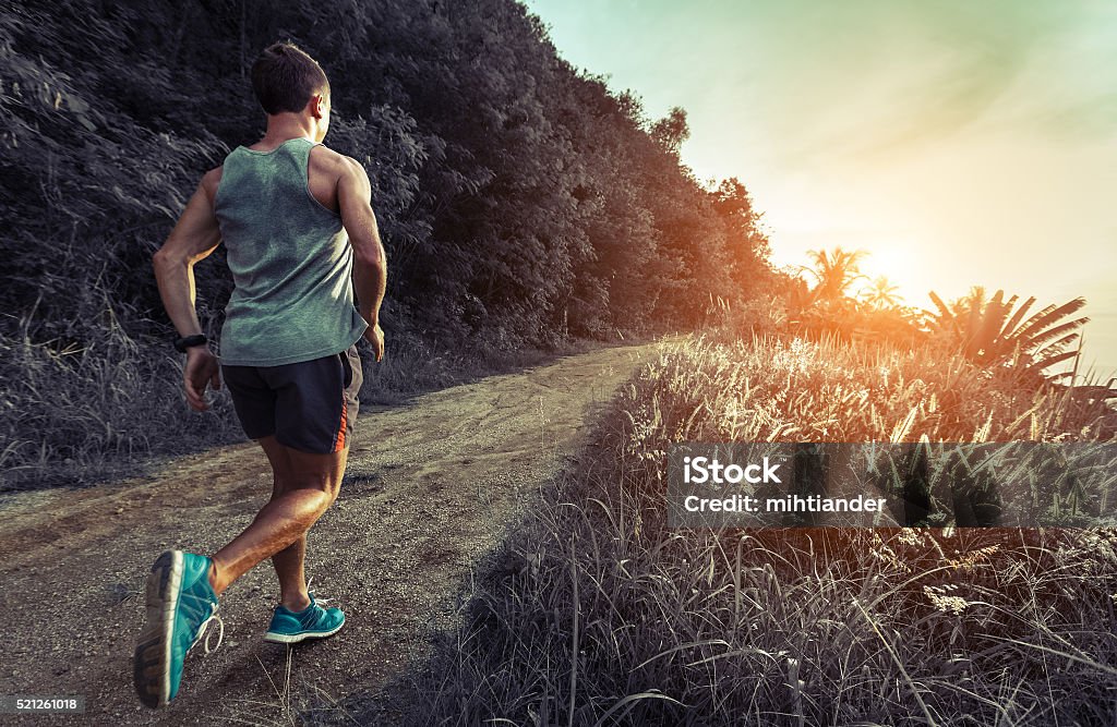 Man jogging on the road Man jogging on the gravel road at sunset Dirt Road Stock Photo