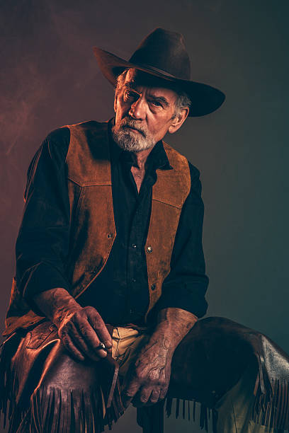 タバコの喫煙旧粗い西部のカウボーイにグレイのヒゲます。 - cowboy hat real people red gray ストックフォトと画像