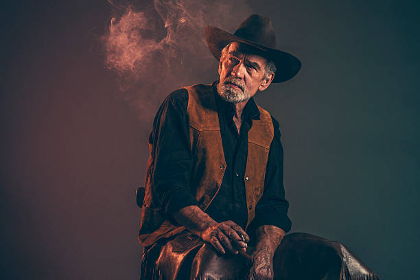 istock Cigarette smoking old rough western cowboy with gray beard. 521261275