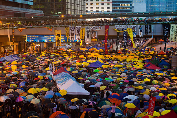 Hong Kong, Hong Kong S.A.R. – October 28, 2014: Pro-democracy protesters holding umbrellas at a blockaded road in Admiralty, Hong Kong, marking one month of \