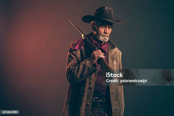 Senior Cowboy With Gray Beard And Brown Hat Holding Rifle Stock Photo - Download Image Now