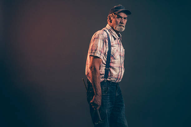 istock Senior carpenter with gray hair and beard holding a hammer. 521262785