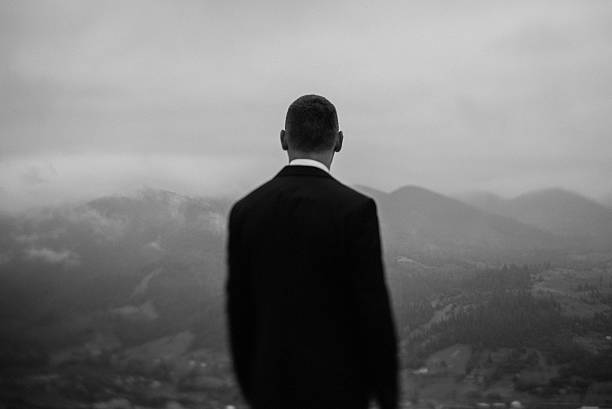 istock Handsome young groom standing in front of mountains and looking 521264136