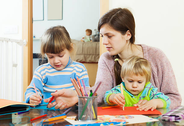 istock Mother and two children together with pencils 521264231
