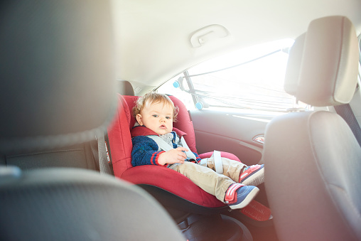 Baby boy strapped into his car seat on a journey.