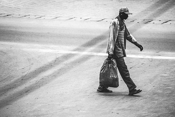 Washington, D. C. homeless person on bench covered with rug or blanket with garbage bag possessions. Horizontal.-For more homeless, click here.  HOMELESS 
