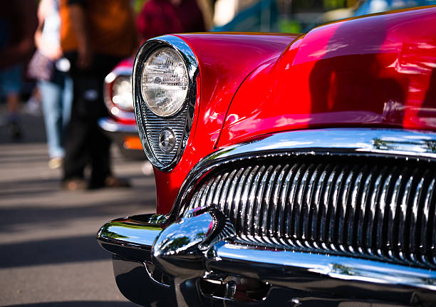 Red retro vintage chrome car details Retro Vintage red car with chrome accents headlamp grille and bumper reminiscent of the outline face predatory sharks in traditional outdoor exhibition of old cars in a small American provincial town. collectors car stock pictures, royalty-free photos & images