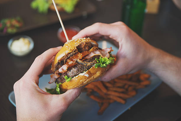 男性が手で、バーガーとフライドスイートポテト - burger gourmet hamburger steak ストックフォトと画像