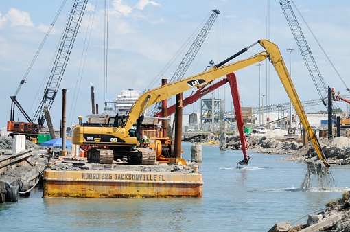 Port Canaveral, Florida,USA - October 20, 2014: Backhoes on barges dredge the area in front of a dock under construction.  The new pier will accomodate the largest cruise ships and is due to open at the end of 2014.