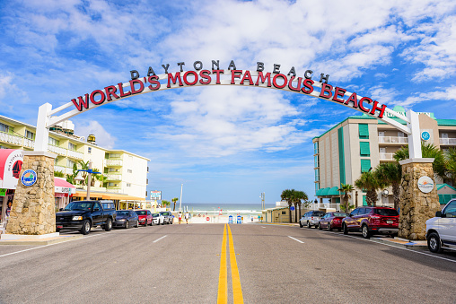 Daytona Beach, FL, USA - February 2, 2015: Beachgoers in the distance walk below the Daytona Beach welcome sign. The popular spring break destination is dubbed \