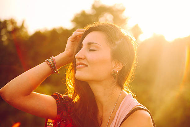 Vintage toned portrait of a smiling young brunette in direct sunlight, wearing an oriental cardigan. Taken in the magic hour as the sun started to set behind the trees with Canon 5d mark 2 and Sigma 28-75 large aperture zoom lens at f2.8